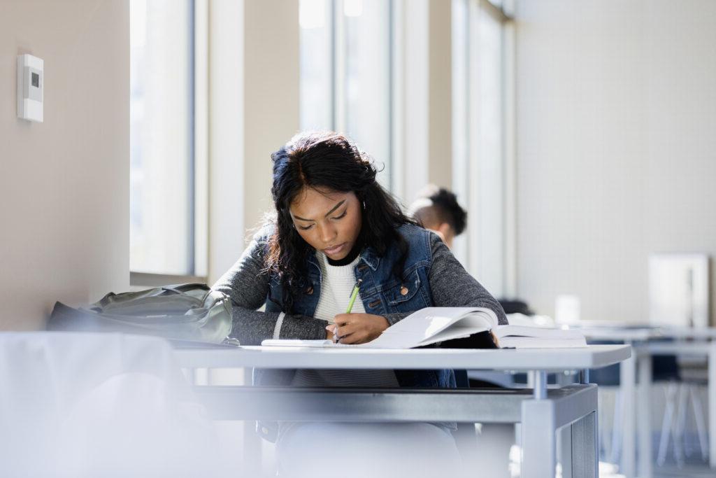 The young woman is focused on reading through her textbook.